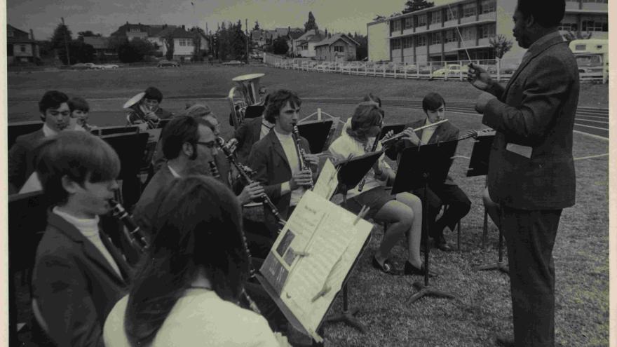 high school band playing outdoors in a field with adult band leader