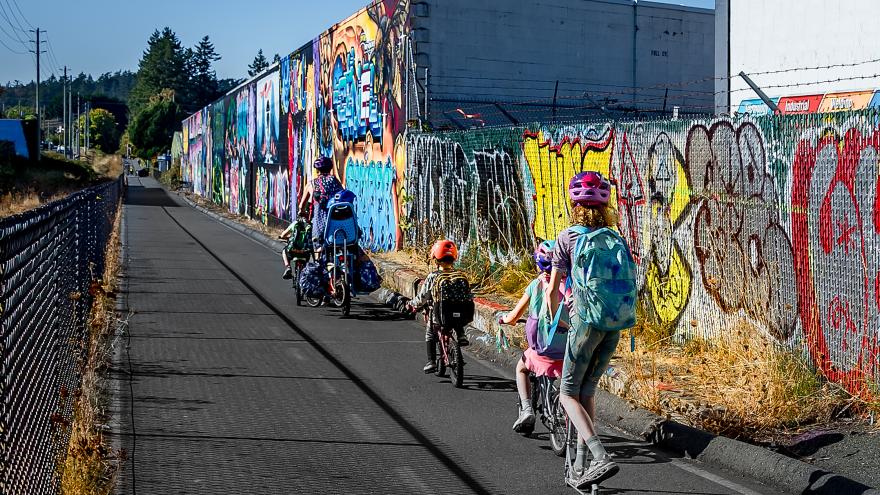 Cyclists on E&N trail next to the Trackside Gallery (graffiti murals)